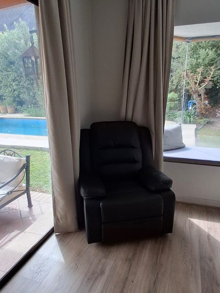 Sillón reclinable negro en el dormitorio de un cliente, con vista al jardín