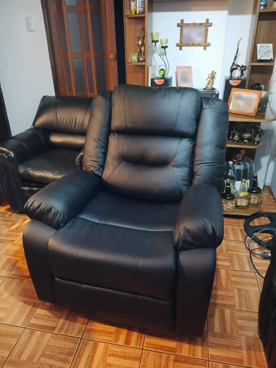 Sillón reclinable negro en el living de un cliente, junto a una repisa